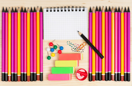 Colorful pencils with notepad and school accessories over wooden surfaceの写真素材