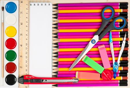 Colorful pencils with notepad and school accessories over wooden surfaceの写真素材