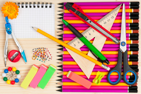 Colorful pencils with notepad and school accessories over wooden surfaceの写真素材