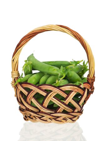 Fresh peas pods in a wicker basket isolated over white backgroundの写真素材