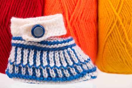 Cute little bootee over bright colorful woolen thread backgroundの写真素材