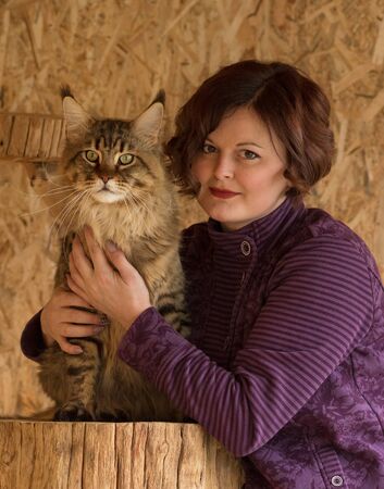 Fluffy Maine Coon cat with young breeder over textured backgroundの写真素材
