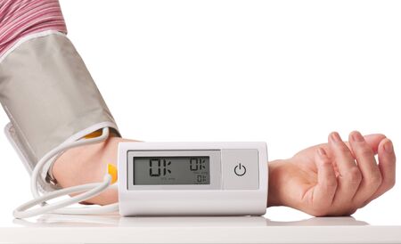 Electronic pressure measuring instrument on the female hand isolated over white backgroundの写真素材