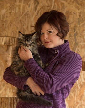 Fluffy Maine Coon cat with young breeder over textured backgroundの写真素材
