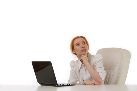 Thoughtful young busineswoman sitting at her laptop staring up into space as she makes difficult decisions or plans a business strategyの写真素材