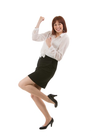 Happy attractive young businesswoman rejoicing at good news balancing on one foot while laughing and punching the air with her fistsの写真素材