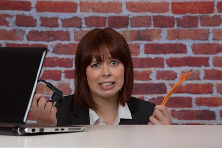 Clueless woman with computer connections held in her hands giving a whimsical expression of confusion indicating her ignoranceの写真素材