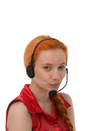Attractive young call centre operator with he long red hair neatly tied in a plait giving the camera an amused smile, isolated on whiteの写真素材