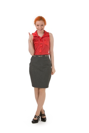 Happy young woman giving a thumbs up of approval and success while standing with her legs crossed smiling at the camera, isolated on whiteの写真素材