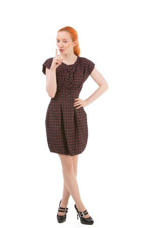 Woman making a hushing gesture asking for silence or indicating that something is secret holding her finger in front of her mouth while pursing her lipsの写真素材