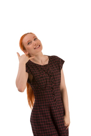 Smiling attractive young redhead woman making a Call Me gesture with her fingers isolated on whiteの写真素材