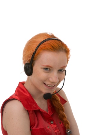 Pretty young redhead call centre operator wearing a headset smiling at the camera , head and shoulders portrait isolated on whiteの写真素材
