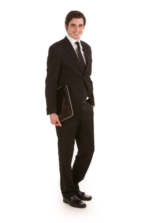 Smart young businessman in a suit standing sideways looking at the camera carrying a black leather folder under his arm, isolated on whiteの写真素材