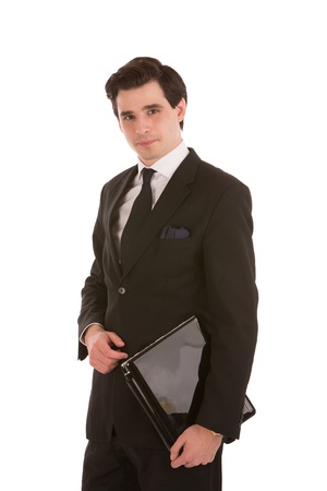 Handsome confident young businessman in a smart suit with a serious expression carrying a black folder isolated on whiteの写真素材