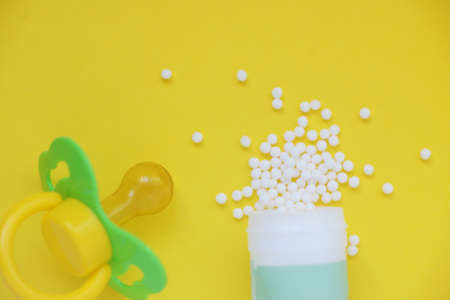 Homeopathic globules and with a plastic jar on a yellow background. Alternative Homeopathy medicine herbs, healtcare and pills concept. Flatlay. Top view. copyspace for text. Homeopathy for childrenの写真素材