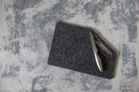empty cutting granite board on concrete gray background with alumene, silver, sharp knife. Top view, flatlayの写真素材