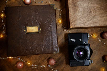 Gift photo book in a leather cover in a wooden plywood box with a vintage black camera. Vintage photo album. Semeinfe photographs of the life of one person. concept of christmas present to family.の写真素材