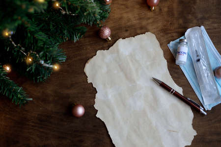 wish sheet on a wooden background with the numbers 2021. dear Santa blank sheet of paper, mask, syringe, covid-19 vaccine, led is a garland. Christmas composition.の写真素材