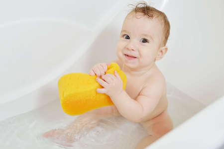 wet kid indulges in the bathroom. time for a dip in the tub. Happy baby having a bath and smiling....
