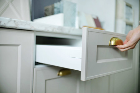 Home improvement concept. young girl designer opens a drawer of a kitchen cabinet in a shop salon.の写真素材