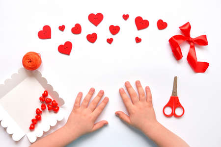 red hearts of different shapes on a solid background. gift wrapped in craft paper wrapped with white gift ribbon. space for text.の写真素材