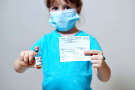 male is holding a vaccination record card and corona virus vaccine vials. Passport of immunity to the coronavirus in the hands of a male. Health passport as proof of recovery from COVID-19の写真素材