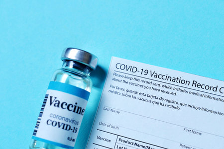 male is holding a vaccination record card and corona virus vaccine vials. Passport of immunity to the coronavirus in the hands of a male. Health passport as proof of recovery from COVID-19の写真素材