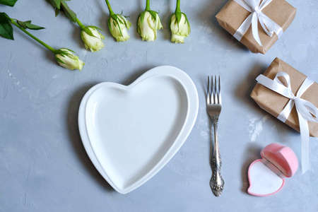 empty white plate with hearts on Ultimate Gray background with white roses and fork. The moment of a wedding, anniversary, engagement, or Valentines Day. Happy day. pink blank gold jewelry boxの写真素材