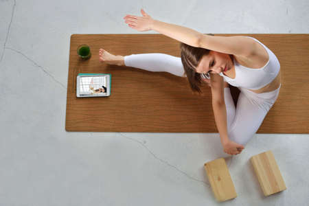 Beautiful brown-haired young woman wearing white sportswear practicing yoga, is engaged with the...