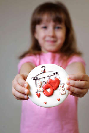 girl in a pink t-shirt holds a gingerbread valentine card. gift for valentine's day. congratulations...