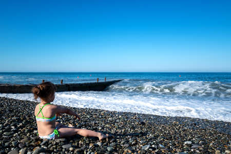 dad takes pictures of his daughter and shoots a video on his phone as she plays by the sea. the concept of a joint holiday with a child. fathers dayの写真素材