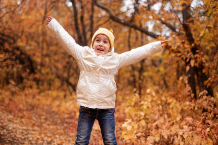 preschooler girl happily runs through the autumn colorful forest. The concept of rest in the forest in autumnの写真素材