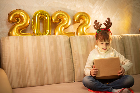 girl child in a white T-shirt with a red pen and a New Year's cap on his head writes dear Santa a letter at the table in anticipation of the birth. wish list of gifts for the new yearの写真素材