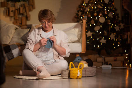 woman knits baskets with a thread key in a cozy house on Christmas evening. family Christmas traditions.の写真素材