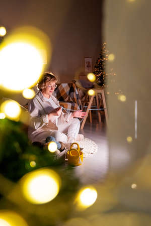 woman knits baskets with a thread key in a cozy house on Christmas evening. family Christmas traditionsの写真素材
