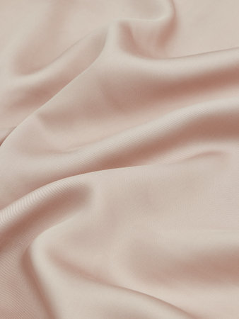 Close up of rippled light pink satin fabric background.の写真素材