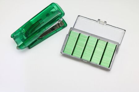 green Stapler and pin on a white background.の写真素材