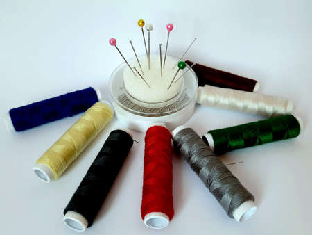 Beautiful colored threaded bows and tailoring needles with colored thread background, bobbin color,...