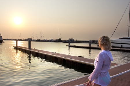 woman looking at the sunset on berth for yachtsの写真素材