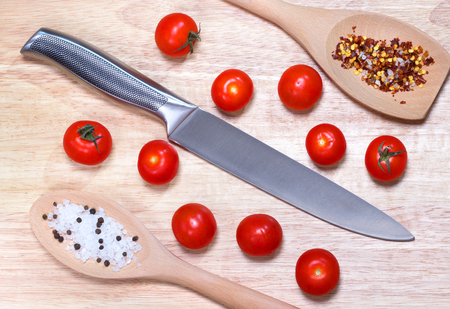 Fresh vegetables - tomato cherry and knife on wooden board on table background. Top view. Healthy food concept.の写真素材