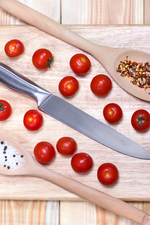 Fresh vegetables - tomato cherry and knife on wooden board on table background. Top view. Healthy food concept.の写真素材