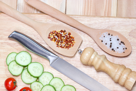 Sliced cucumber,cherry tomatoes, spice on wooden cutting board.Healthy food concept.The process of cookingの写真素材