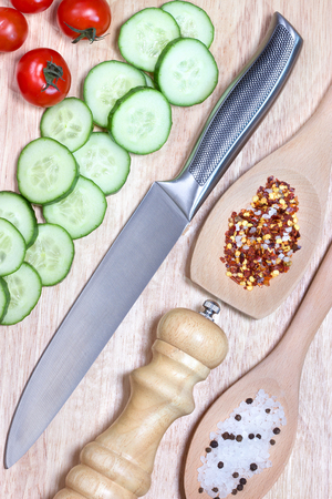 Sliced cucumber,cherry tomatoes, spice on wooden cutting board.Healthy food concept.The process of cookingの写真素材