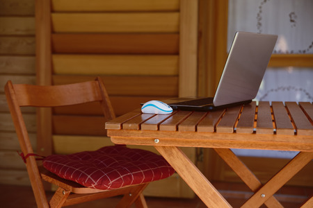 nomad work concept image with computer on wood table and sunlight, blurred trees of nature park background and summer season.の写真素材