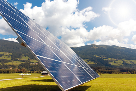 solar panels against mountains landscape against blue sky with clouds and sun shine. Solar power...