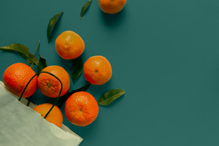 Ripe tangerines in a paper bag on a green backgroundの写真素材