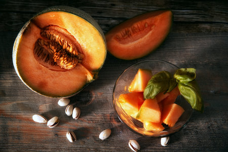 Whole and sliced ripe organic cantaloupe melon on wooden background.Ripe cantaloupe-melon slices in a dish.rustic cozy atmosphere.の写真素材