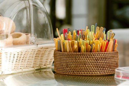 Colorful clothespins in a wicker basket on a glass tableの写真素材