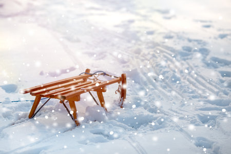 Wooden bench and sled on snow, space for text. Winter vacationの写真素材