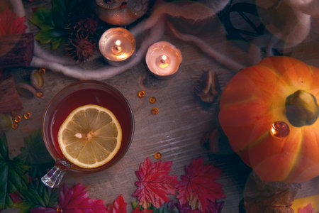 A cup of tea with lemon on a wooden table, next to candles.の写真素材